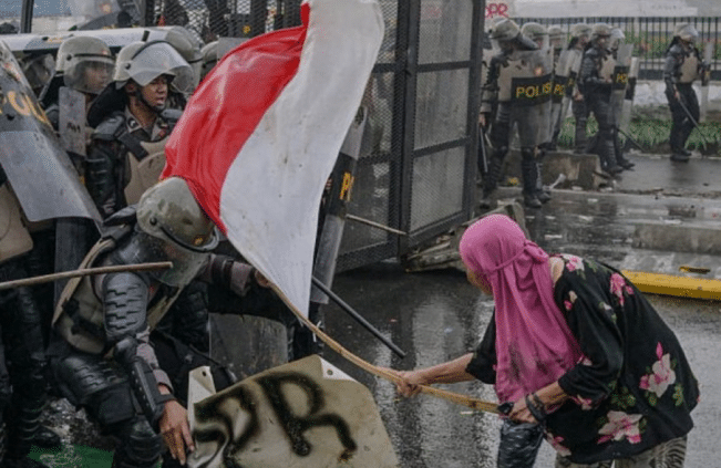 Seorang ibu berkerudung pink menghadapi aparat (foto: insertlive)